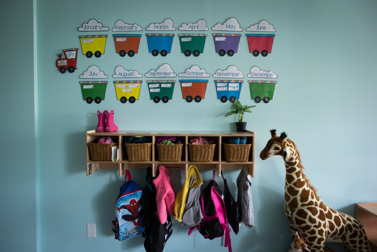 Children's backpacks and shoes are seen hanging on a wall. 