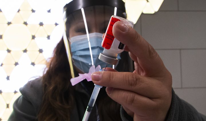 A heath worker wearing a face mask and a face shield works at a COVID-19 vaccination clinic in Toronto on April 4, 2022.