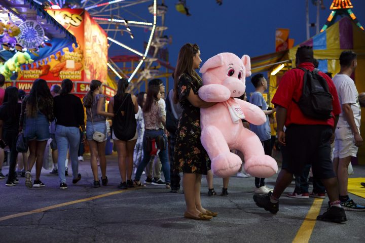 A woman holds a prize at a carnival game at the 140th annual Canadian National Exhibition in Toronto on Sunday, August 19, 2018. 
