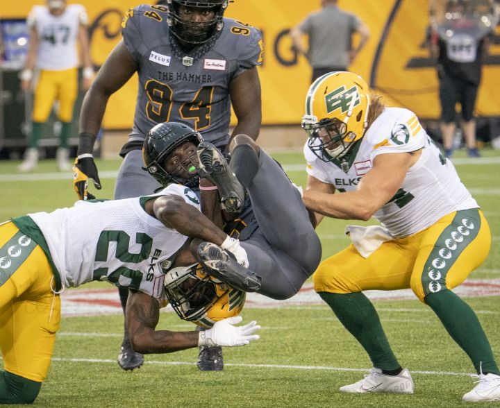 Hamilton Tiger Cats defensive back Lawrence Woods (37) isn tackled by Edmonton Elks defensive back Mike Dubuisson (29)and Ante Milanovic-Litre (34) during first half CFL football game action in Hamilton, Ont. on July 1, 2022.