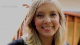 Caitlin Jensen smiles at the camera. She has long blonde hair and is wearing a dark top.