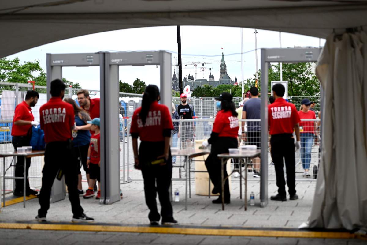 Staff working at the Canada Day concert wait at a security checkpoint.