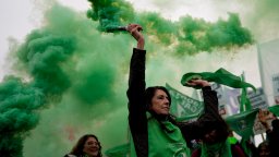 An abortion rights protester deploys green smoke at a rally.