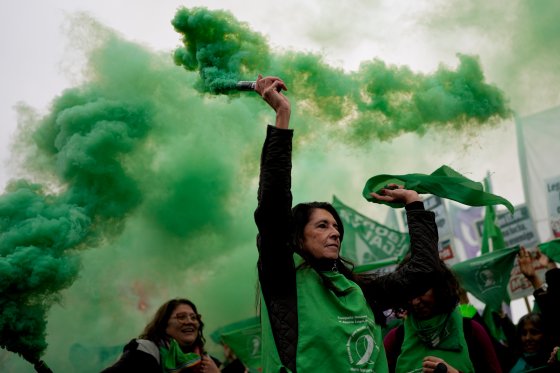 An abortion rights protester deploys green smoke at a rally.