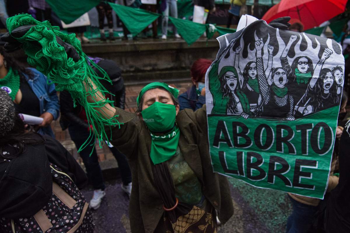 Abortion rights protesters in Colombia wear green in a crowd.