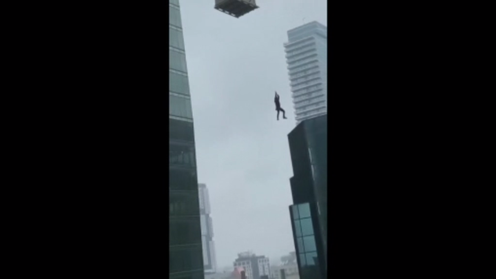 Videos show construction worker dangling from crane in Toronto