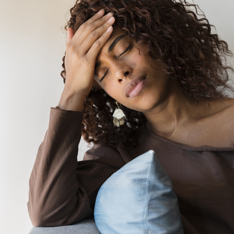 A young Black woman with headache holding her head