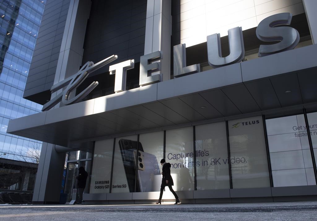 A woman walks in front of the Telus head office is shown in Toronto on Thursday, February 11, 2021. Telus Corp. wants to pass on credit card fees to customers, and plans to tack on a 1.5 per cent "processing fee" starting this fall. 