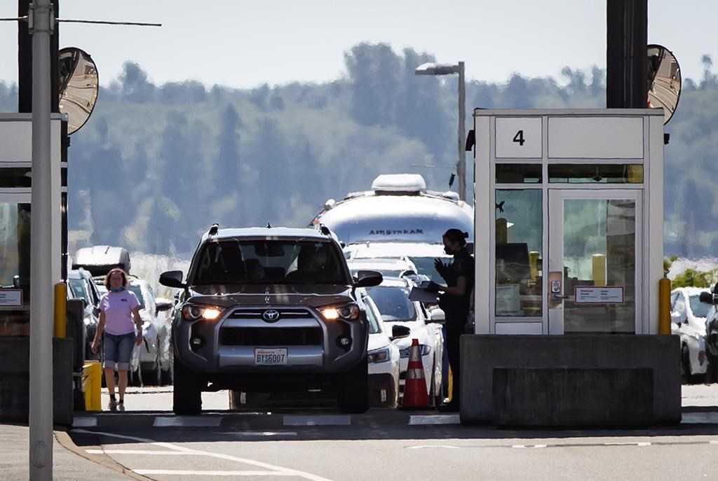A Canada Border Services Agency officer speaks to a motorist entering Canada at the Douglas-Peace Arch border crossing in Surrey, B.C. on Aug. 9, 2021. THE CANADIAN PRESS/Darryl Dyck
