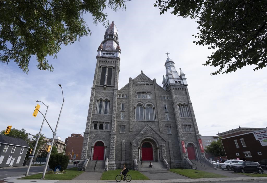 A person rides their bike past a decommissioned church, Thursday, August 18, 2022 in Ottawa. An Ottawa-based group with suspected ties to the “Freedom Convoy” says it has been threatened with eviction and is ready to take its cause to court in an attempt to set up headquarters in the country's capital. 