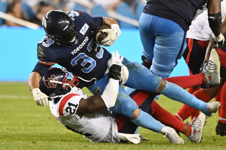 Toronto Argonauts running back Andrew Harris (33) is tackled by Montreal Alouettes linebacker Chris Ackie (21) during first second CFL football action in Toronto Thursday, June 16, 2022. 