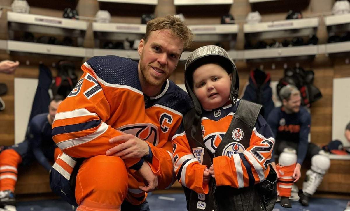 Ben Stelter, a young Edmonton Oilers fan with cancer, poses with Connor McDavid in the team's locker room earlier in 2022.