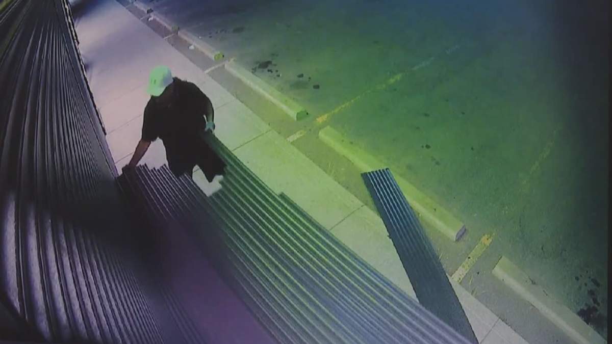 One person is seen disassembling security shutters on Omkara Cannabis in Calgary on Aug. 18, 2022, in an apparent attempt to gain entry.