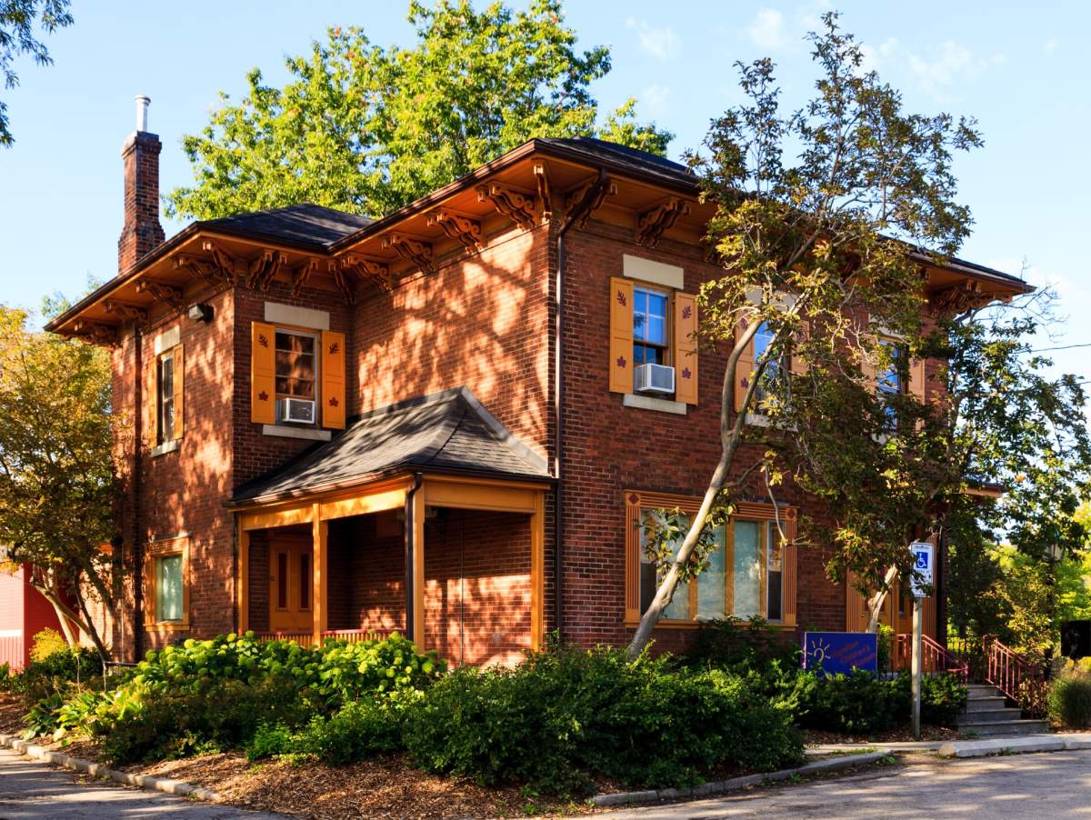 A large brown-brick house with orange trim around the windows and porch.