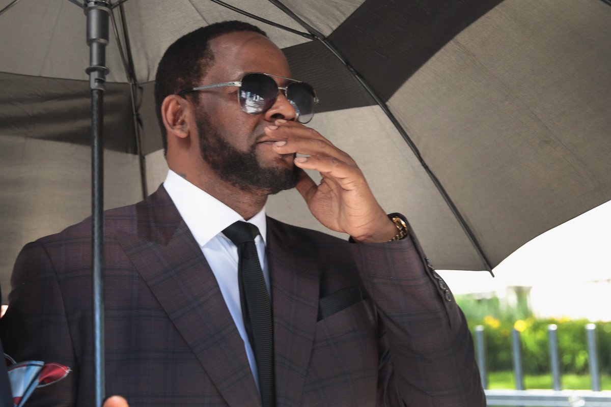 R. Kelly in a suit under an umbrella