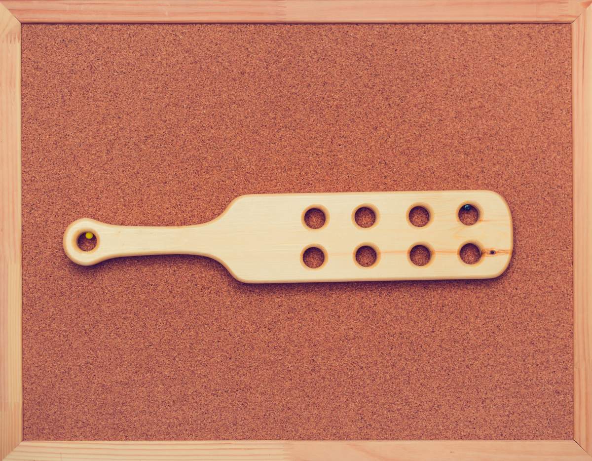 Wooden paddle for spanking on cock board on the wall.