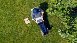 an aerial view shows a man using laptop in garden