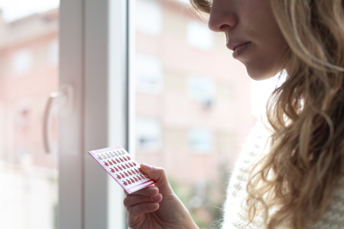 Close up of young woman holding contraceptive pills at home