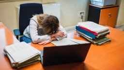 Exhausted woman lying on table in office