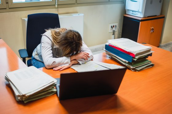 Exhausted woman lying on table in office