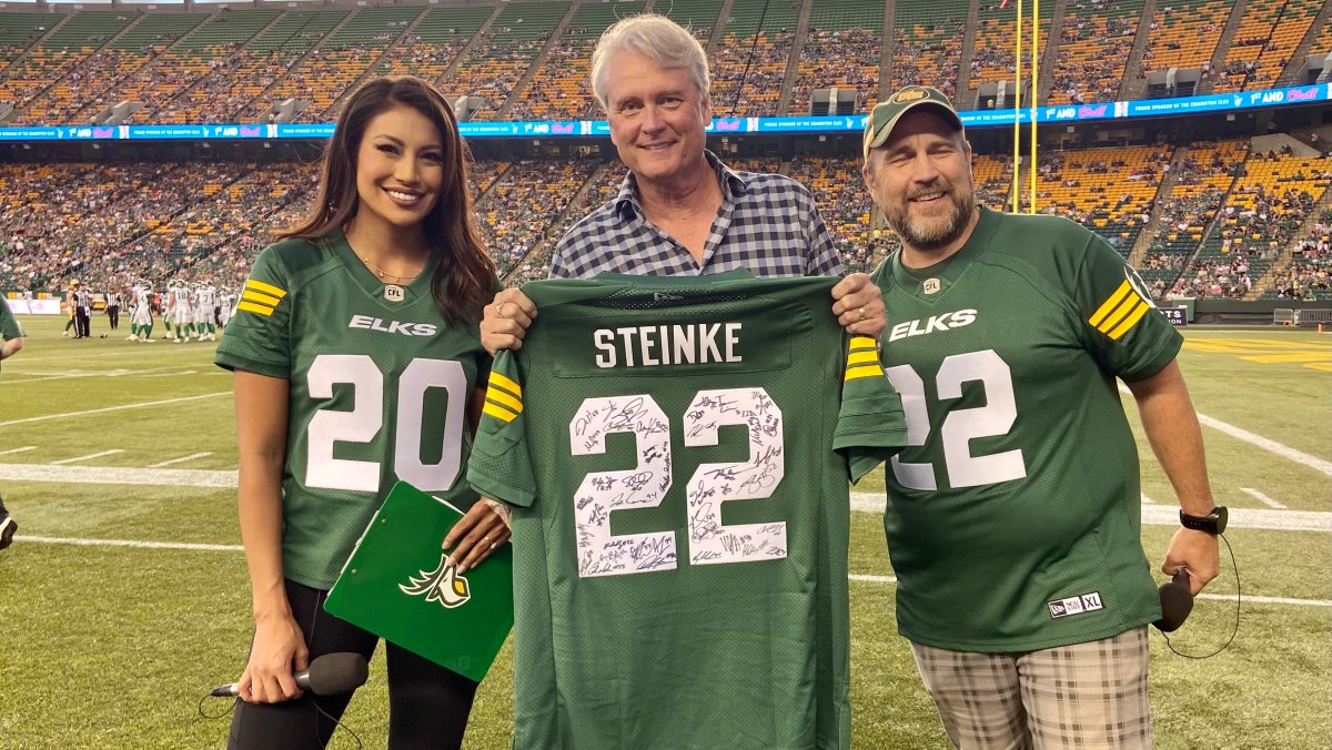 Global News Anchor Gord Steinke receiving his honourary Edmonton Elks jersey Saturday, Aug. 13, 2022 from game hosts Ashley Callingbull (left) and .