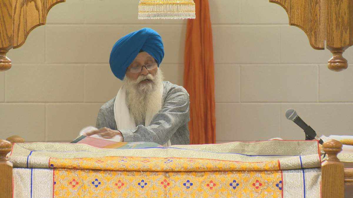 Priest at Grudwara located at 3905 Princess Drive turning the pages of the Guru Granth Sahib.