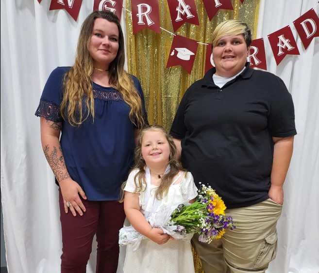 Zoey poses with her parents, Jennie (L) and Emily Parker (R). Zoey was asked to leave her school for having same-sex parents.