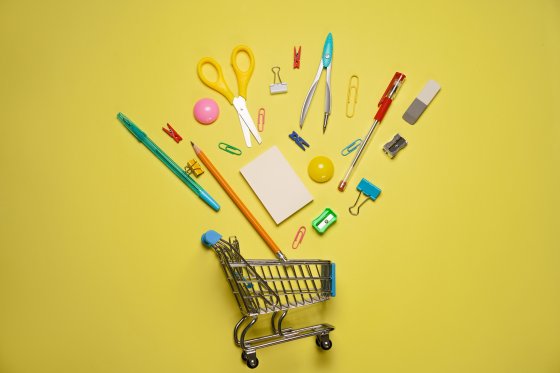 Trolley cart with school supplies on a yellow background. Flat, top view. Back