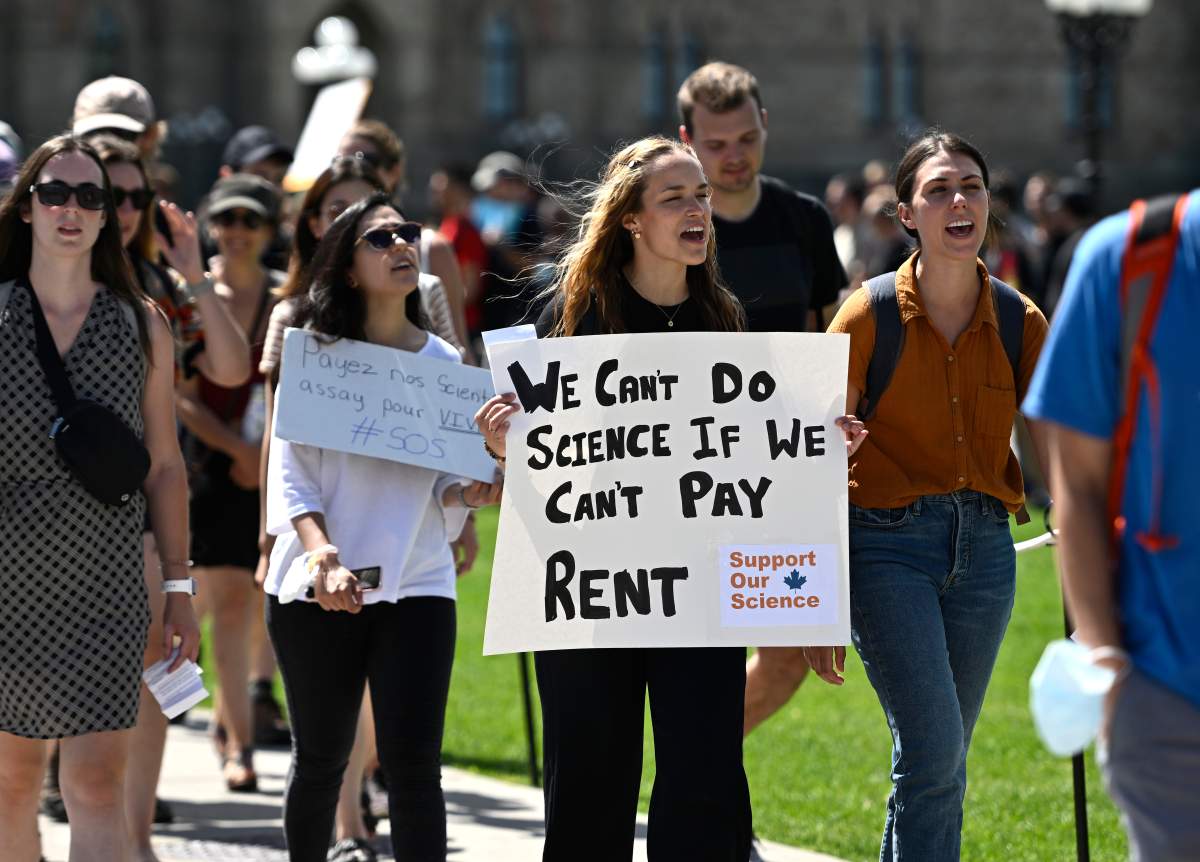 Post-doctorate students carry a long letter of signatures calling on the government to increase grants to them.