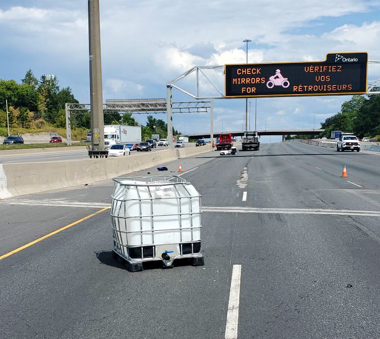 Police are investigating after a tote fell from a vehicle and struck a motorcyclist along Highway 401.
