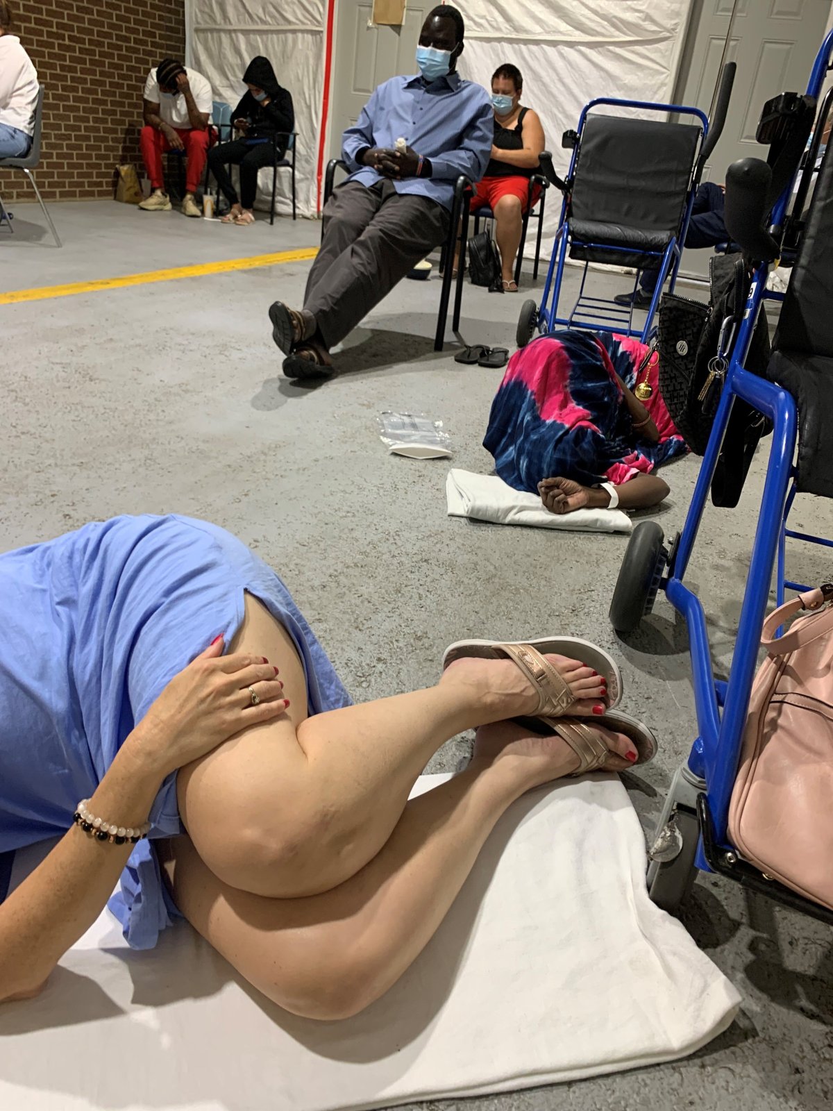 Trista Champagne, 47, laying on the floor of a waiting area at the Misericordia Community Hospital emergency department in Edmonton, Alta. on Sunday, Sept. 4, 2022.