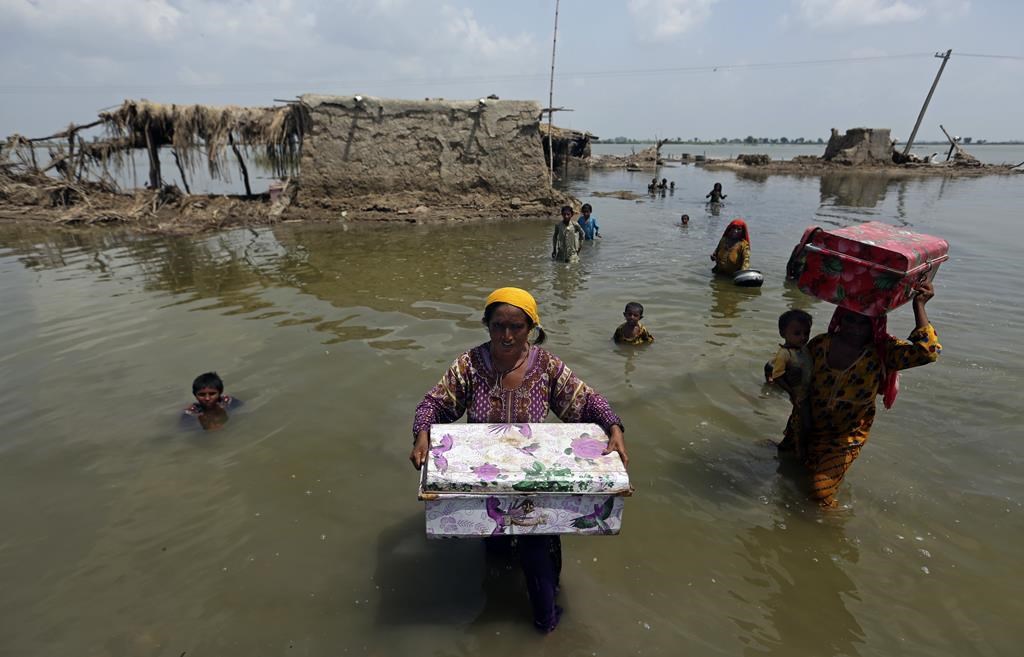 A Pakistani women carrying her belongings through the flood