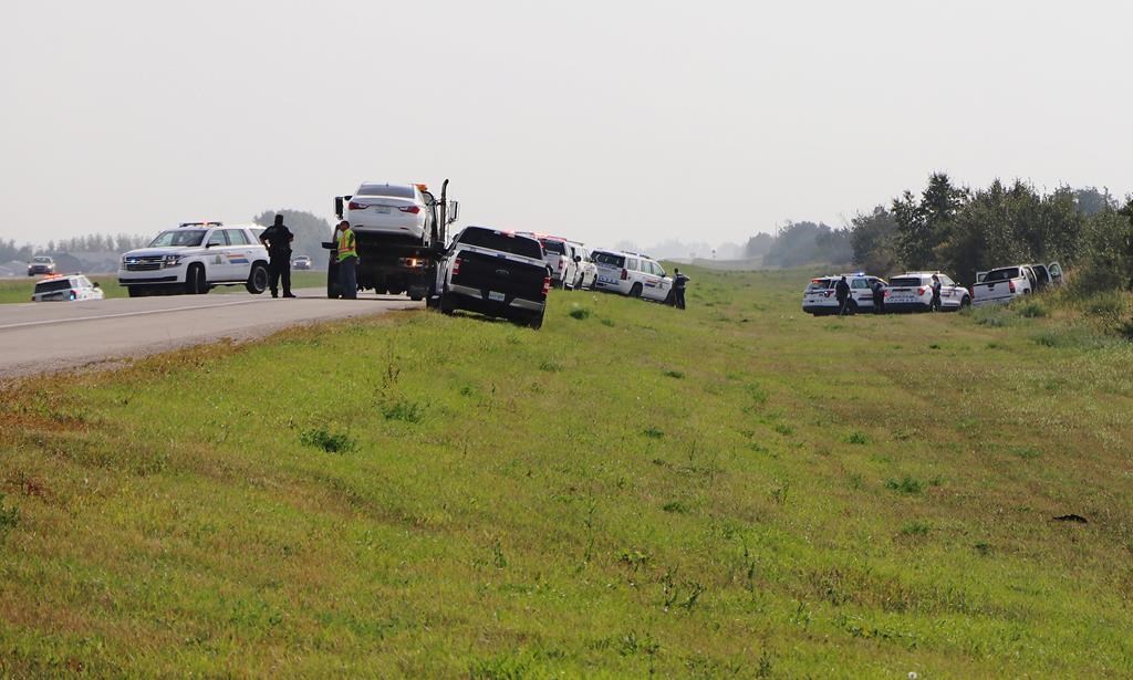 Police and investigators after Sanderson’s stolen car was shunted off the road. THE CANADIAN PRESS/Kelly Geraldine Malone