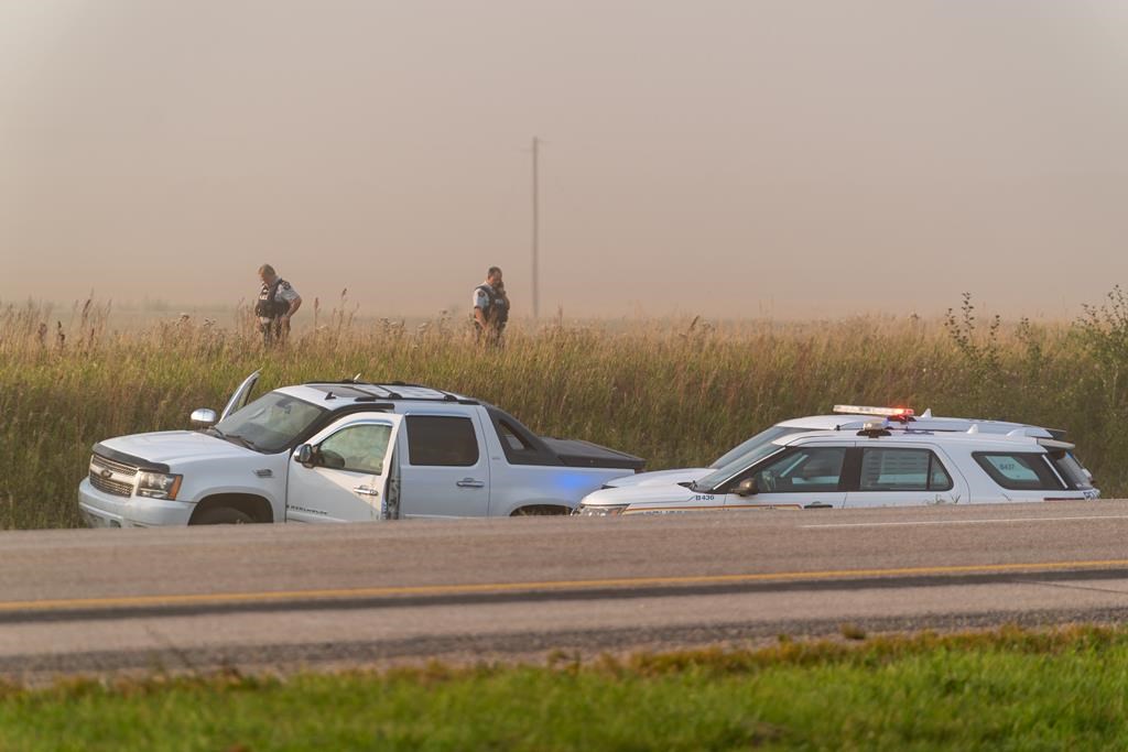 Police and investigators are seen at the side of the road outside Rosthern, Sask., on Wednesday, Sept. 7, 2022. The chief of a Saskatchewan First Nation is to speak the day after the suspect in a deadly stabbing rampage died after being taken into police custody. Myles Sanderson went into medical distress shortly after being arrested Wednesday, bringing an end to a four-day manhunt. THE CANADIAN PRESS/Heywood Yu.