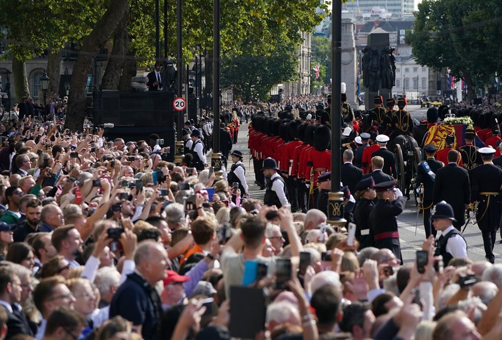 The coffin of Queen Elizabeth II, draped in the Royal Standard with the Imperial State Crown placed on top, is carried on a horse-drawn gun carriage of the King's Troop Royal Horse Artillery, during a procession for the Lying-in State of Queen Elizabeth II from Buckingham Palace to Westminster Hall in London, Wednesday, Sept. 14, 2022.