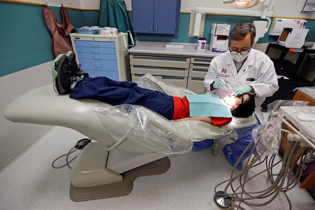 A dentist at the Riley Hospital for Children Department of Pediatric Dentistry, checks the teeth of Justin Perez, 11, during an office visit in Indianapolis, Friday, Jan. 22, 2016. University of Calgary associate economics professor Lindsay Tedds warns the federal dental benefit for children opens families up to the potential for "clawbacks" if they don't spend all the money on their kids' teeth.