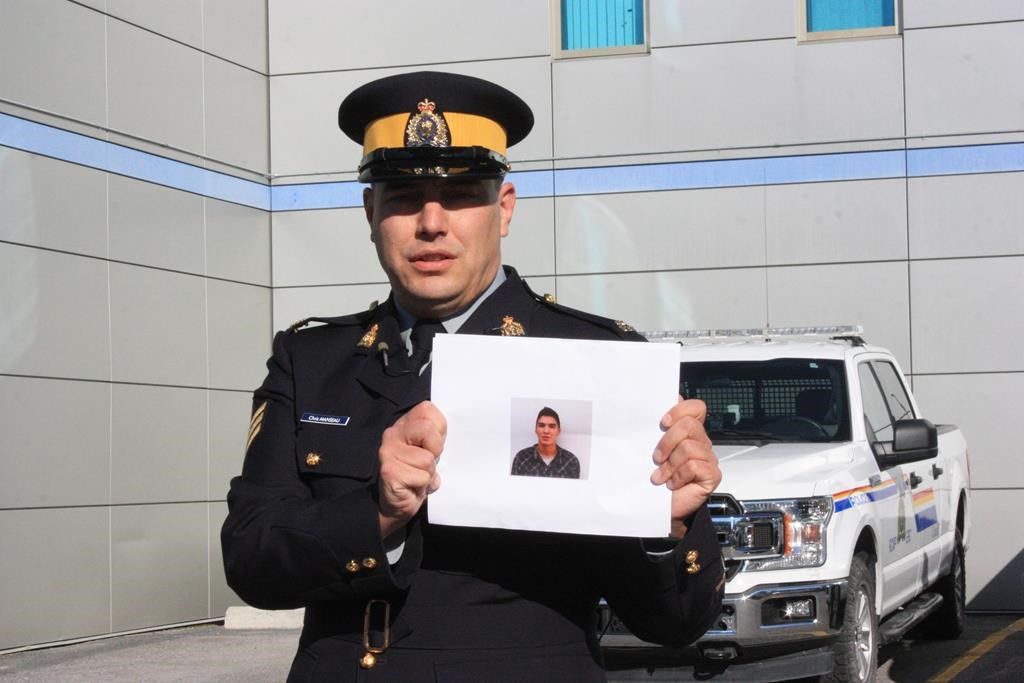 RCMP Sgt. Chris Manseau holds up a photo of Thaddeus McNeely outside of RCMP headquarters in Yellowknife, Thursday, Sept. 22, 2022. Police have identified McNeely, 24, as the lone suspect in a fatal stabbing in Fort Good Hope, N.W.T. THE CANADIAN PRESS/Emily Blake.
