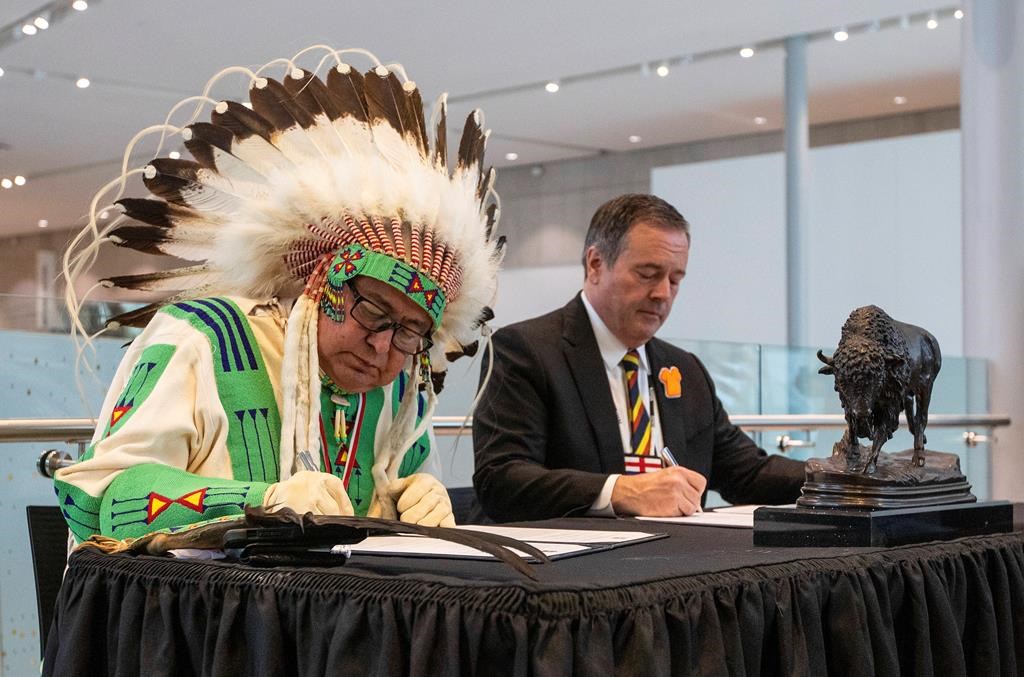 Elder Leonard Bastien, left, and Alberta Premier Jason Kenney, sign a co-stewardship agreement as they announce a new path forward regarding the stewardship of Manitou Asiniy or Manitou Stone, in Edmonton, on Friday, Sept. 30, 2022.