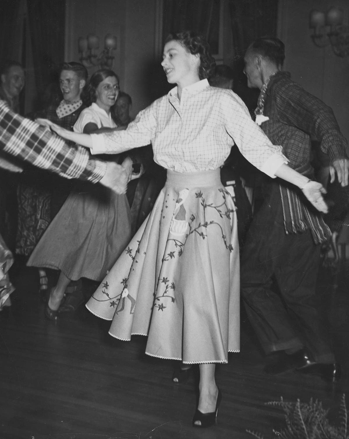 Princess Elizabeth, dressed in a blouse and a flowered, flared skirt, goes through the “swing-your-partner and do-si-do” intricacies at a private square-dance party at Government House in Ottawa, on Oct. 11, 1951.