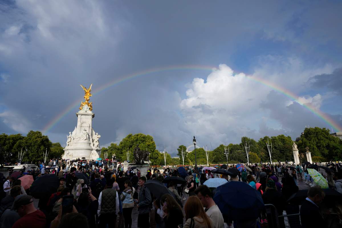 People gather outside Buckingham Palace in London as a double rainbow appears in the sky, Thursday, Sept. 8, 2022.