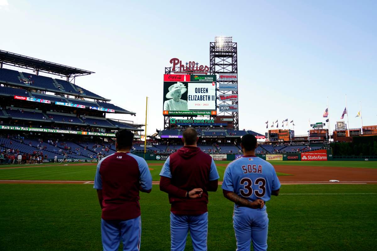 Philadelphia Phillies’ players stand before a baseball game against the Miami Marlins for a tribute to Queen Elizabeth II, Britain’s longest-reigning monarch who died after 70 years on the throne, Thursday, Sept. 8, 2022, in Philadelphia. (AP Photo/Matt Slocum)
