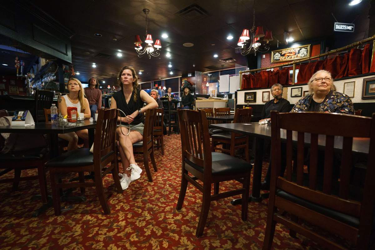 People watch the funeral of Queen Elizabeth on television screens at The Bishop and Belcher pub in Toronto on the morning of Monday, Sept. 19, 2022. THE CANADIAN PRESS/Alex Lupul