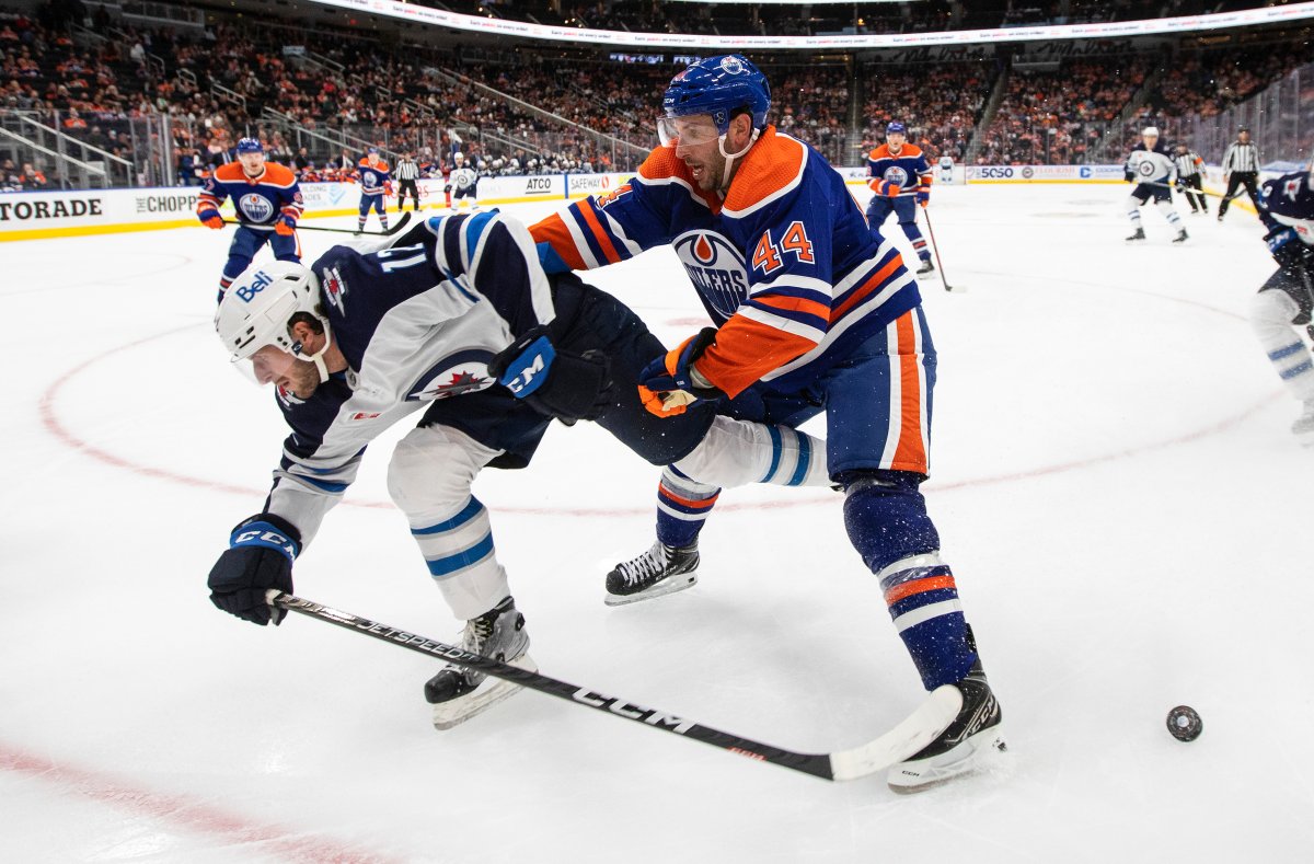 Winnipeg Jets’ Jansen Harkins (12) is checked by Edmonton Oilers’ Jason Demers (44) during third period pre-season action in Edmonton, Sunday, Sept. 25, 2022.