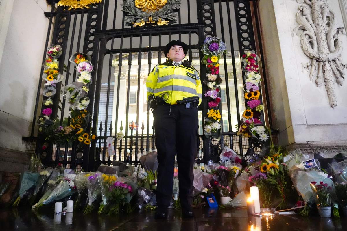 A police officer stands amongst floral tributes left outside Buckingham Palace in central London, following the announcement of the death of Queen Elizabeth II.