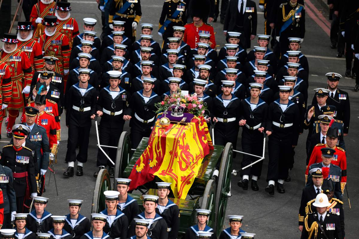 Royal Navy Sailors walk ahead and behind the coffin of Queen Elizabeth II, draped in the Royal Standard, as it travels on the State Gun Carriage of the Royal Navy at Wellington Arch in London, Monday Sept. 19, 2022.