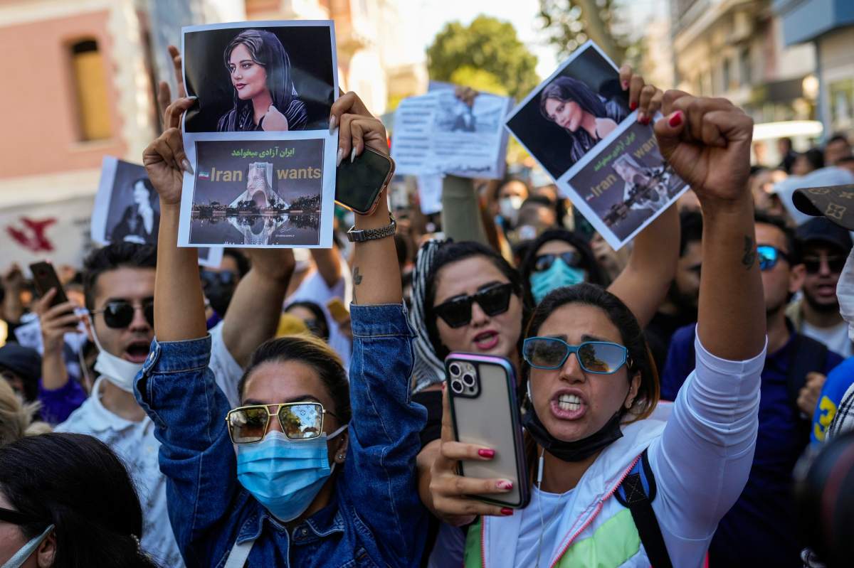 Women holding signs and pictures of Mahsa Amini.