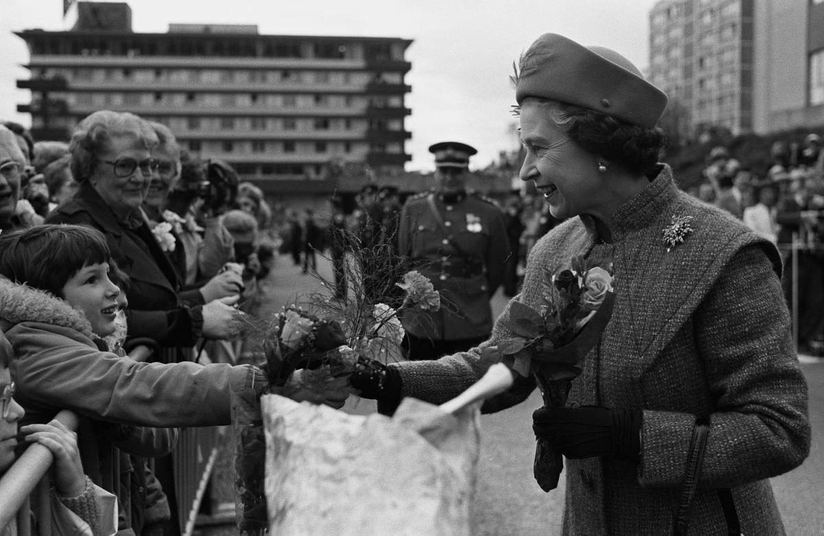 A young girl has the opportunity of a lifetime as she hands Queen Elizabeth II some flowers during the Queen’s visit to New Westminister’s city hall in British Columbia March 10, 1983. (CP PHOTO/Mike Blake)
