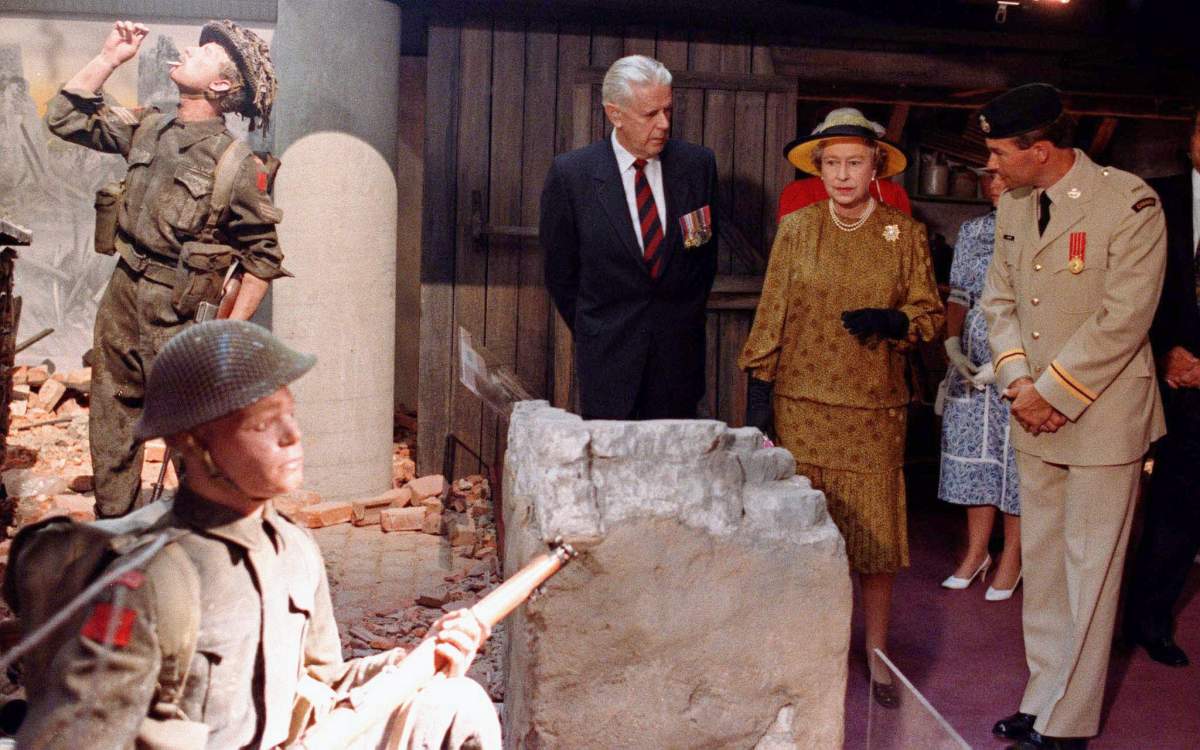 Queen Elizabeth II looks at the displays in the Calgary Military museum escorted by Neil Stewart (left) and an unidentified officer of the Canadian Forces in Calgary, AB, June 30, 1990.