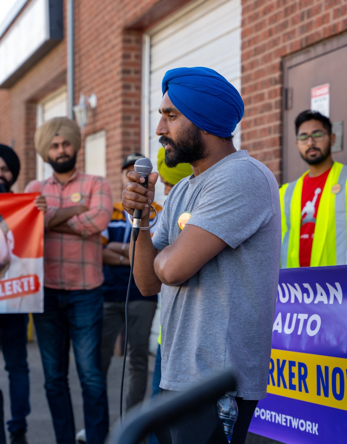 Rupinder Singh speaks to a crowd of supportive protestors in front of a crowd outside his former workplace, Sukh Auto.