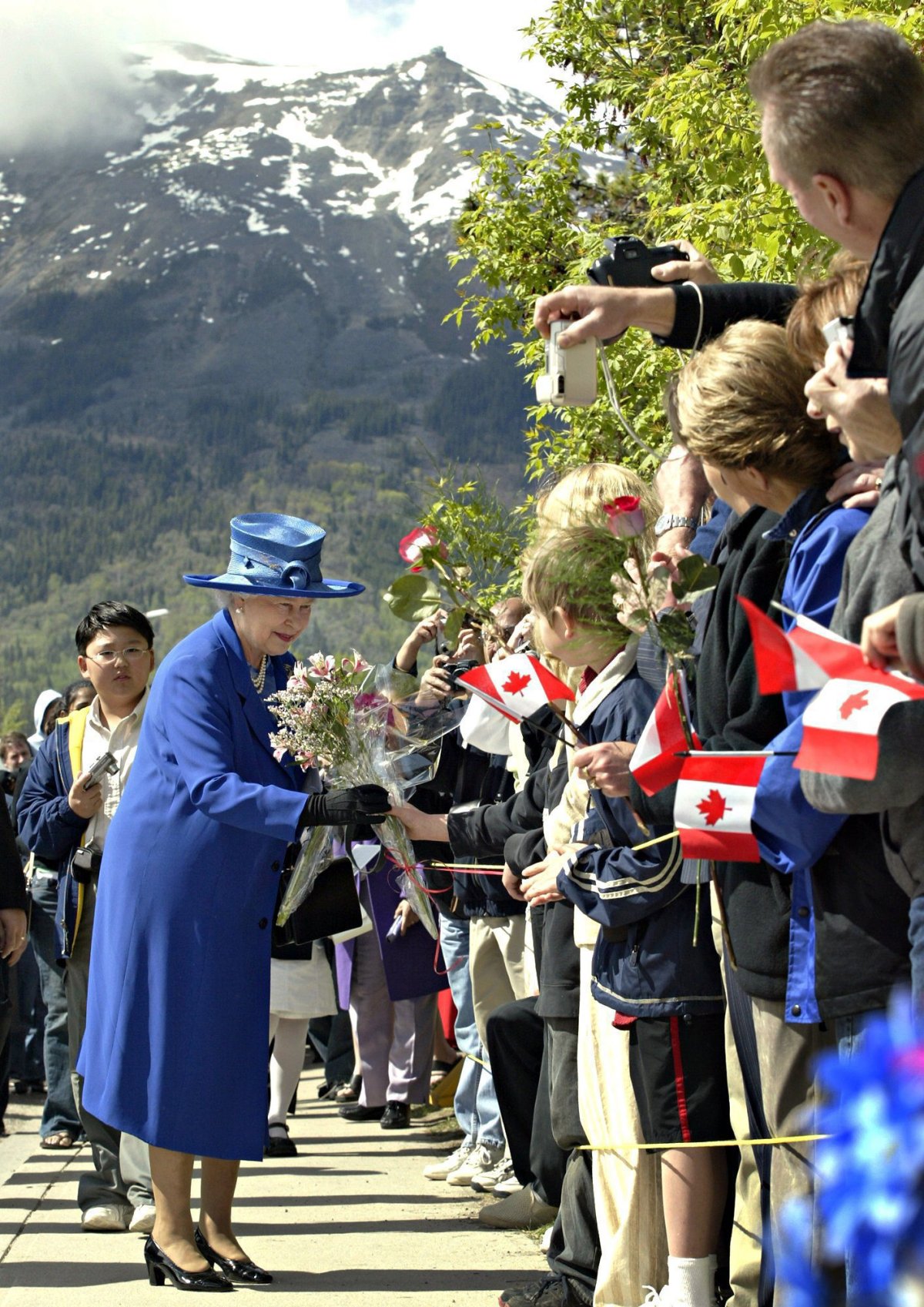 Queen Elizabeth II greets the crowd as she leaves St. Mary’s and St. George Anglican Church following a church service Sunday, May 22, 2005 in Jasper, Alta. with Whistler Mountain in the background.